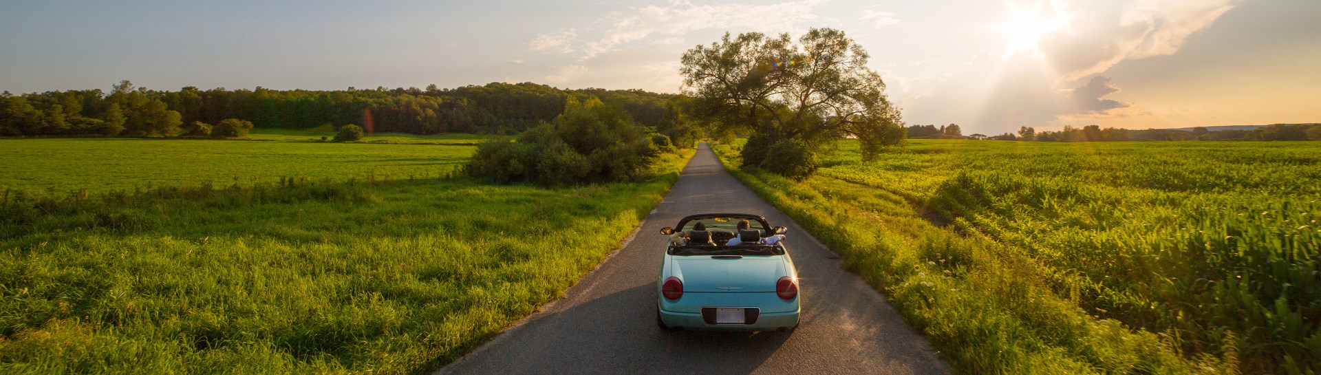 Car driving into sunset