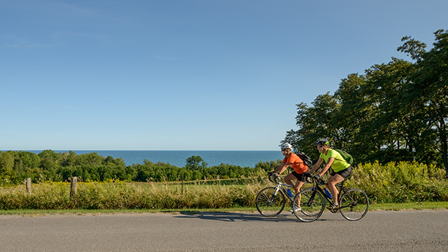 2 cyclists riding on country road near water